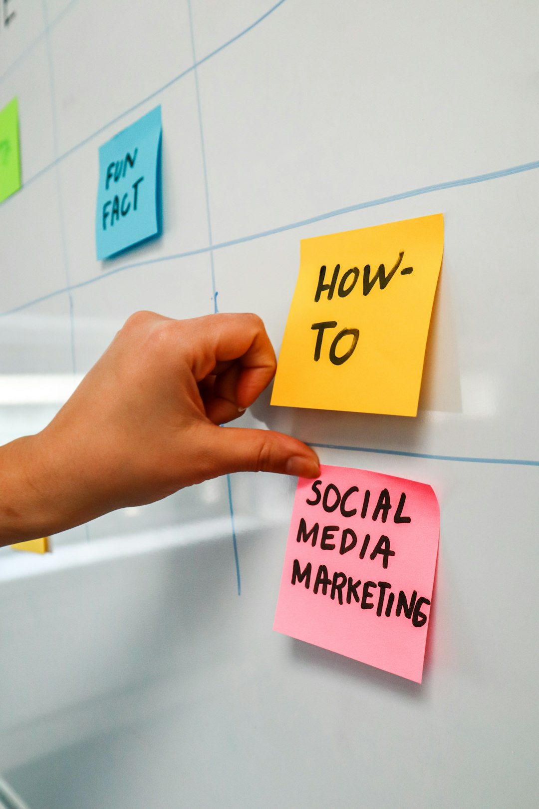hero-img-01 Person sticking a post-it on a white board with the words Social Media Marketing written on it